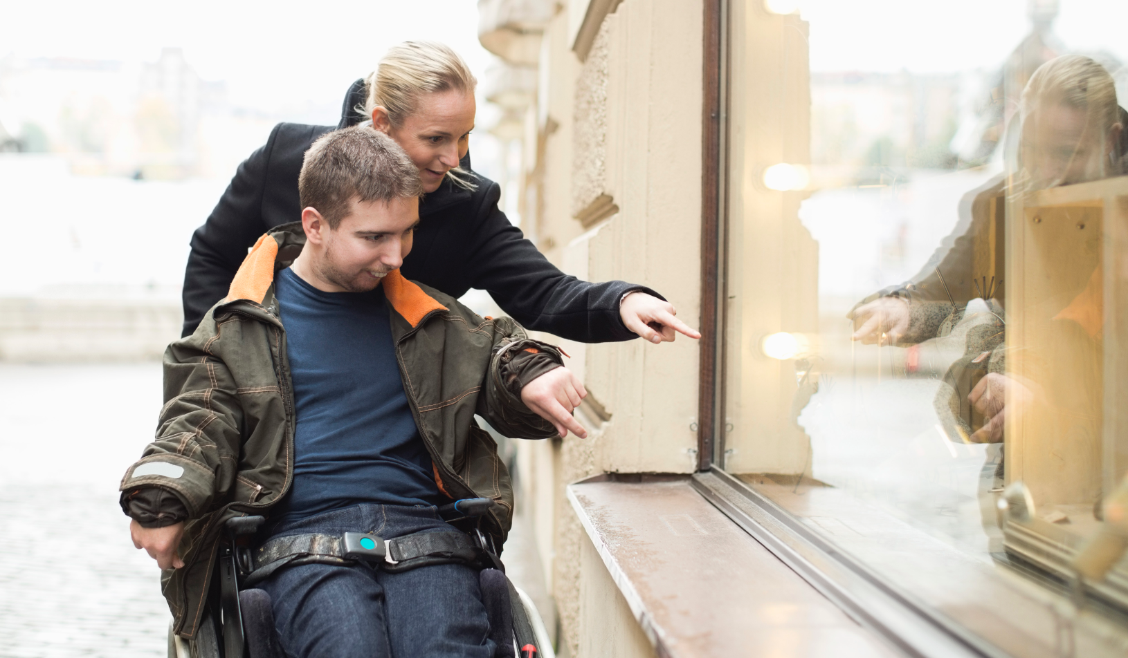 Woman pushing man in wheelchair looking at store windows